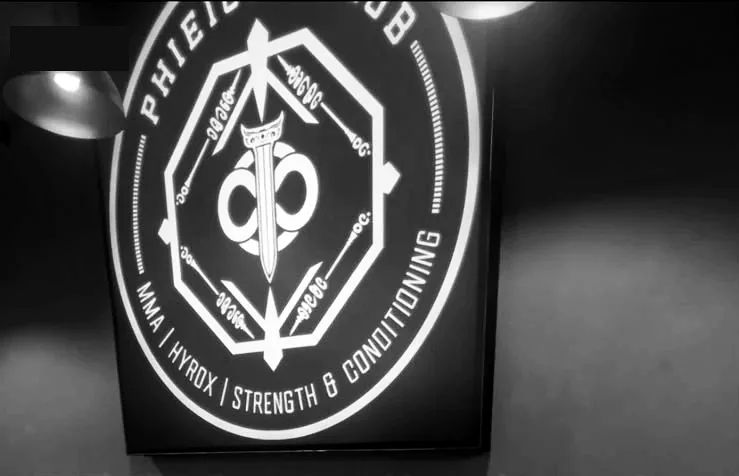 The backlit Phi Eight Club crest on the gym wall